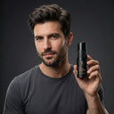 A male model with voluminous, textured and matte hair holding a SHARK DUST men's texture powder bottle in a studio with dark grey background