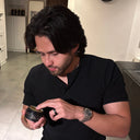 A male model with long, thick hair styling his hair in a Dubai apartment using SHARK MOLD men's hair styling clay