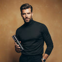 A male model with a voluminous, matte and textured hair style holding a SHARK SURF men's sea salt spray bottle in a studio environment with dark yellow background